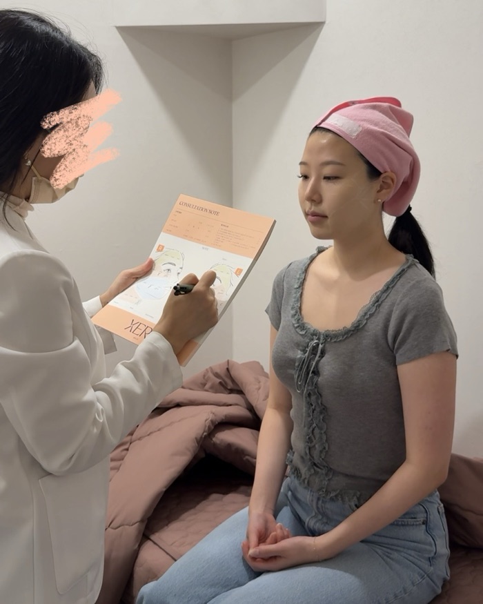 Yerim in a clinic consultation while a practitioner maps out a treatment plan on a consultation note